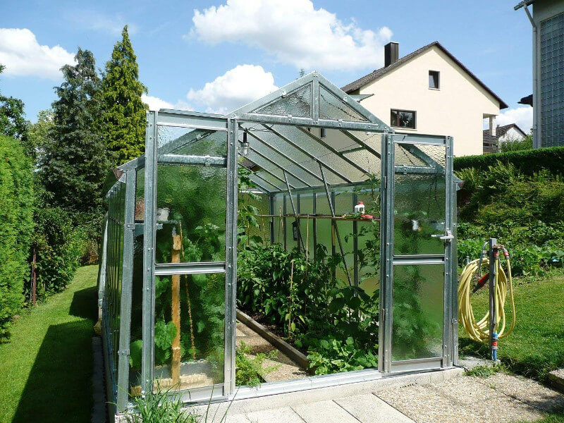 Gewächshaus aus Glas mit offenen Türen zur Veranschaulichung der inneren Pflanzen