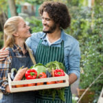 Ein verliebtes Paar hält eine Gemüsekiste in den Händen