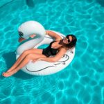 Eine Frau mit einem schwarzen Badeanzug auf einem Schwan im Pool